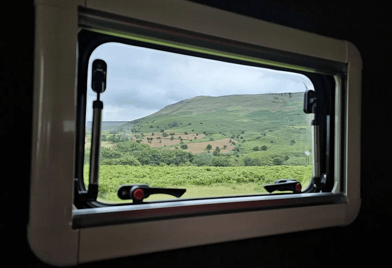 Inside a Wild Camper Truck looking out the kitchen window to the mountains